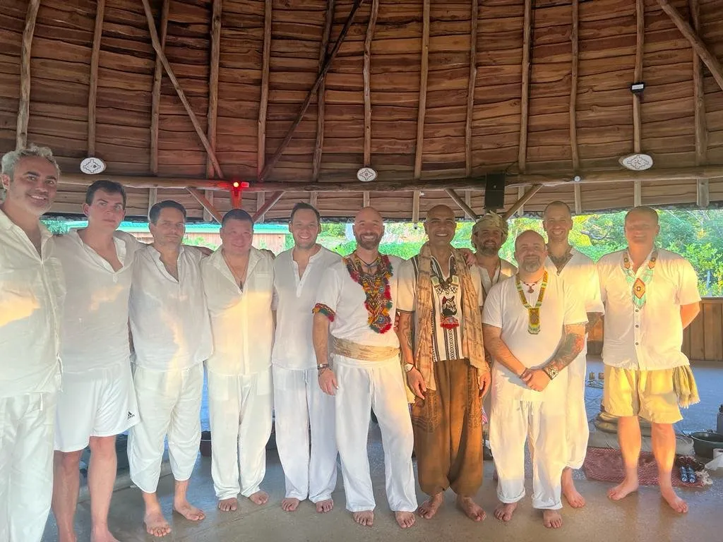 A group of men in white standing with Faisal inside the maloka